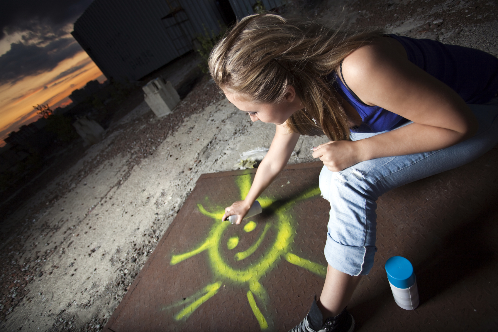 Woman spray painting an image of a happy sun