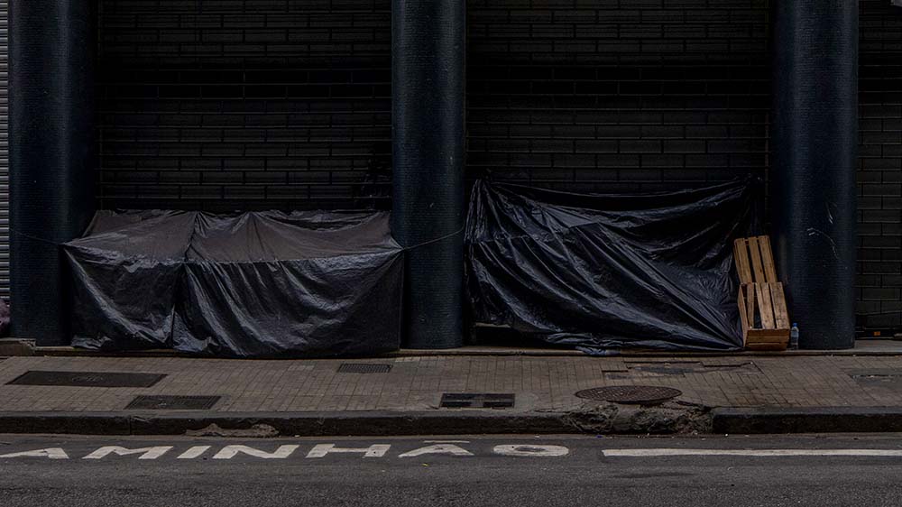 What caught my attention in this photo was the use of the structure of the buildings mixed with plastic, camouflaging itself in the urban environment. Another interesting fact is to see such structures shared between neighboring shelters, which can reveal an idea of sharing and protecting each other.